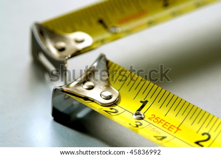 Two self retracting construction tape measures illustrating the maxim or carpentry saying to measure twice and cut once
