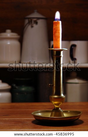 Antique brass candlestick with burning candle in an old general store