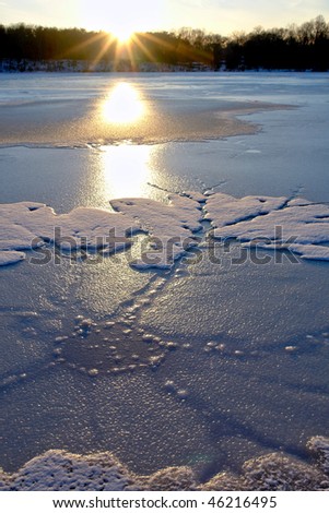 Ice formations of floats and floating sheets on a frozen lake at sunset