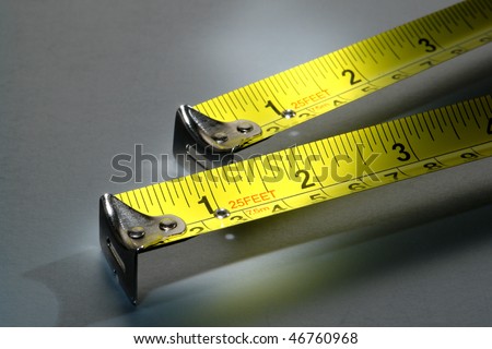 Pair of self retracting construction tape measure illustrating the carpenter famous maxim to measure twice and cut once