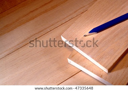 Blue carpenter pencil on red oak wood boards in a carpentry workshop for furniture making