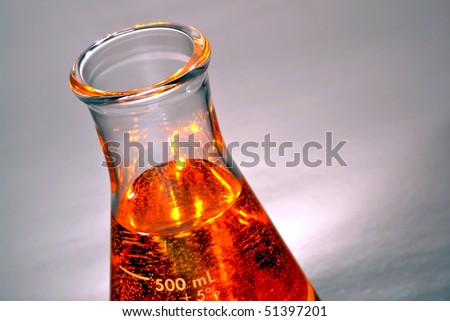 Laboratory glass conical Erlenmeyer flask filled with orange liquid for an experiment in a science research lab