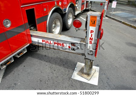 Hydraulic outrigger stabilizing legs extended on a ladder fire truck in a street
