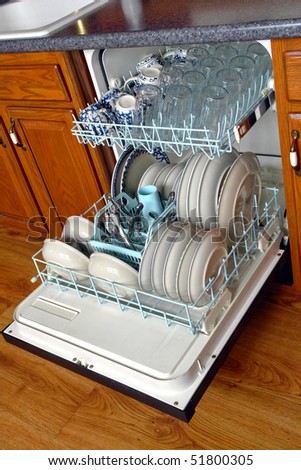 House dishwasher appliance open and loaded full with dirty dishes ready for washing with racks pulled out in a modern kitchen