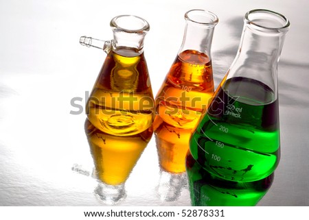 Laboratory glass conical Erlenmeyer flasks filled with green liquid and yellow chemical for an experiment in a science research lab
