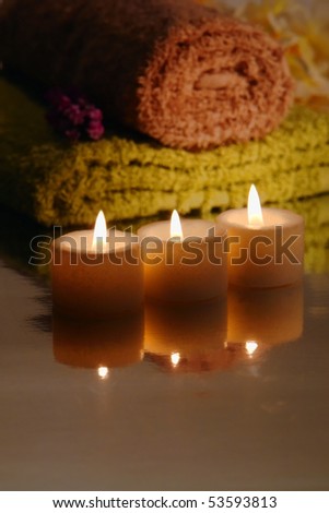 Votive candles burning with a soft glow with towels in a spa