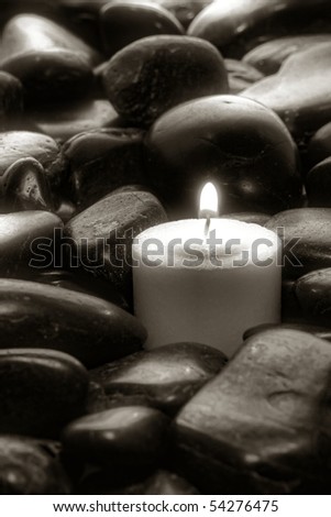 Meditation votive candle burning in a bed of stones in artistic black and white