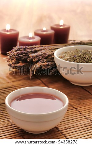 Hot massage oil in a bowl with dried lavender flowers and seeds for a relaxing aromatherapy body care treatment session in a spa