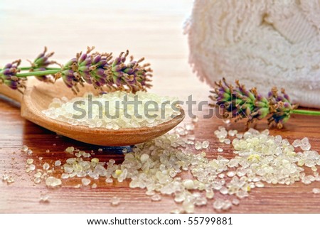 Natural sea bath salts in a wood spoon with fresh cut lavender flowers and white towel in an aromatherapy spa