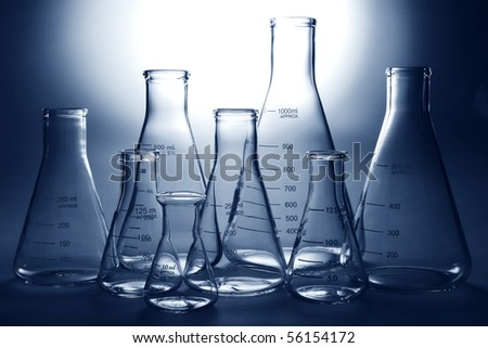 Clear and empty laboratory glass conical Erlenmeyer flasks of assorted sizes ready for an experiment in a science research lab over white