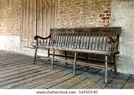 Old wood sitting bench on a distressed historic building porch