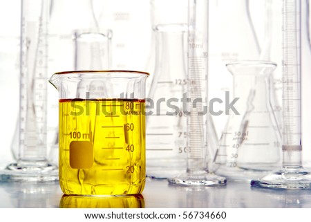 Graduated beaker filled with yellow liquid and laboratory glassware for an experiment in a science research lab