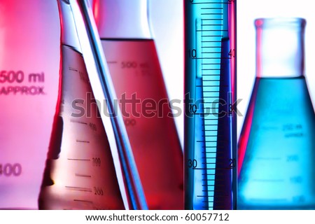 Scientific laboratory graduated cylinder filled with blue liquid and conical Erlenmeyer flasks full of aqua and pink chemical solution for an experiment in a science research lab