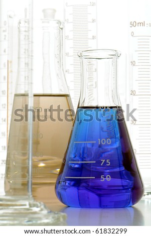 Laboratory glass conical Erlenmeyer flasks filled with blue liquid and grey chemical solution for an experiment in a science research lab