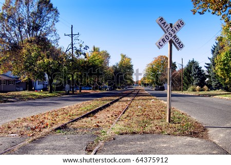 Old abandoned railroad train track line with crossing sign through a street in a small American town