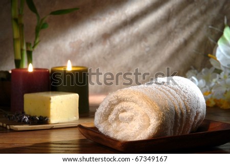 Soft white cotton towel in wood dish with candles burning for a pampering relaxation treatment in a spa