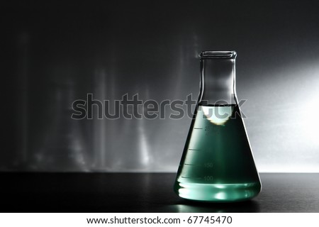 Laboratory glass Erlenmeyer flask filled with green liquid for an experiment in a science research lab