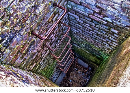 Mysterious and colorful stairway ladder down a concrete and brick lined fortification bunker shaft well