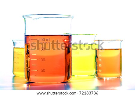 Assorted sizes laboratory glass scientific beakers filled with orange and yellow chemical liquids before a chemistry experiment in a science research lab