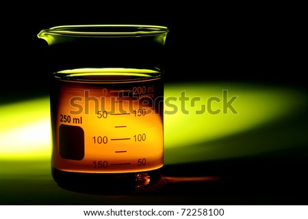 Laboratory glass scientific beaker filled with orange chemical liquid for a chemistry experiment in a science research lab