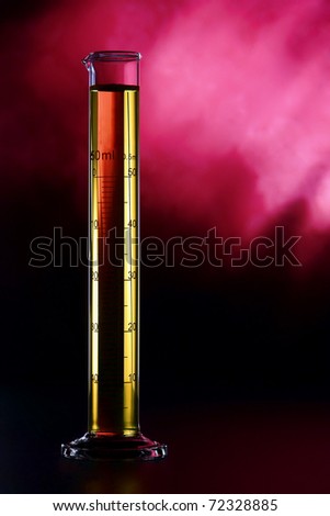 Graduated scientific laboratory glass cylinder filled with yellow liquid chemical solution over pink smoky background during a medical exploration experiment in a science research lab