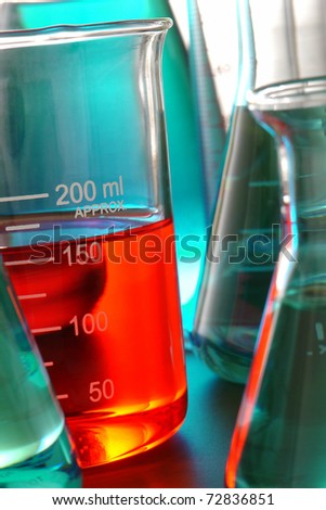 Laboratory glass scientific beaker filled with red chemical liquid and conical Erlenmeyer flasks for a chemistry experiment in a science research lab