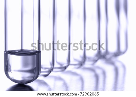 Test tubes with small amount of chemical liquid at the bottom of one in a row of empty clear glass vessels for an applied discovery chemistry experiment in a science research lab