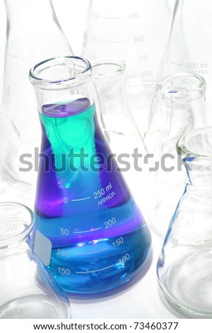 Laboratory glass Erlenmeyer conical flasks with single one filled with blue chemical liquid for a chemistry experiment in a science research lab