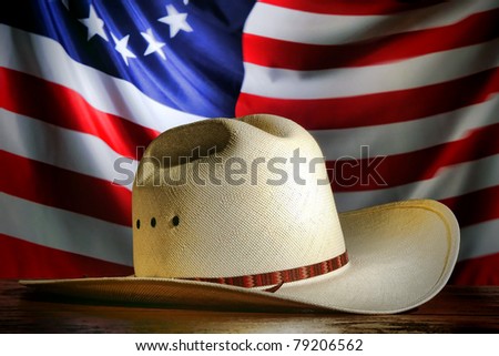 American West rodeo cowboy traditional white straw hat over waving old and antique historic US flag at a patriotic Western event
