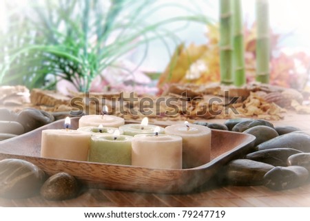 Votive candles burning with a soft glowing flame in a wood dish in a natural exotic environment with smoke haze over a lush tropical vegetation background during a spiritual Zen meditation session