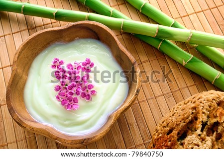 Pink flowers in cosmetic treatment body and facial skin rejuvenation cream in wood bowl bamboo stems and natural organic sponge for a pampering relaxation session in an aromatherapy and wellness spa