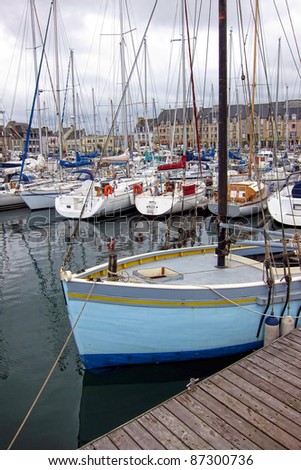 Fishing sail boat moored at dock with fleet of small pleasure crafts in the Paimpol harbor port marina in Brittany France