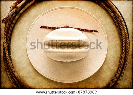 American West rodeo cowboy white hat and authentic vintage Western lariat style lasso hondo loop on smooth brown leather texture background