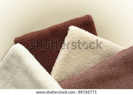 Soft and fluffy cotton hotel quality bath towels in light beige to dark brown fashion colors over soft leather surface