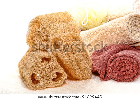 Natural loofah skin cleansing care and exfoliating scrub sponge with soft cotton bath towels for a pampering hygiene and relaxation treatment in a spa