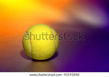 Bright fluorescent yellow color felt tennis sport regulation ball over colorful yellow and purple background