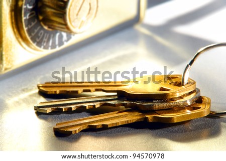 Set of house keys on a ring and real estate brokerage Realtor agent combination safety lock box on shiny reflective surface