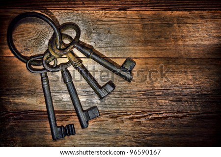 Antique and rusty medieval castle skeleton door keys with old corroded metal ring on antique weathered barn wood board planks