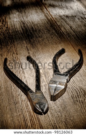 Vintage used and rusty pliers pairs tools on antique grunge weathered wood board workbench in an old carpentry shop