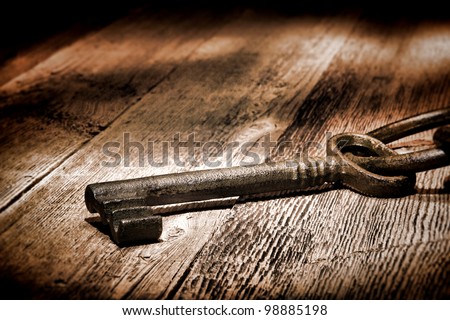 Antique medieval skeleton door lock key on old and weathered wood planks