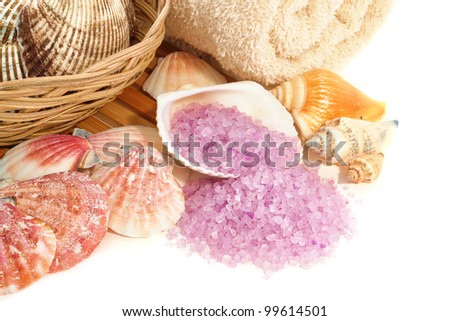 Natural aromatherapy purple bath sea salts spilling out of a shell and decorative seashells assortment for a pampering relaxation and rejuvenation session in a spa over white