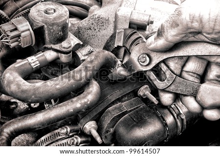 Auto repair mechanic greasy hand with dirty grease holding pliers tool to fix damaged hose needing motor parts replacement on car engine during an automobile shop maintenance installation service call