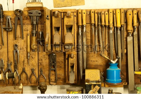 assortment of do it yourself tools hanging in a wooden cupboard against a wall