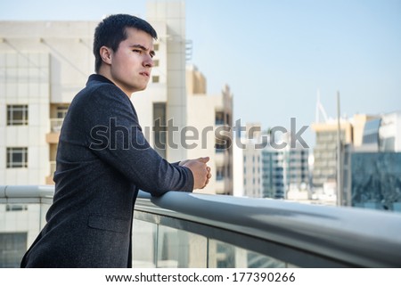 man looking on city standing at the balcony