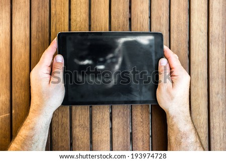 Man holding tablet pc in hands on wooden background