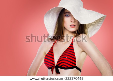 Beautiful fashion woman in white hat and red swimsuit posing