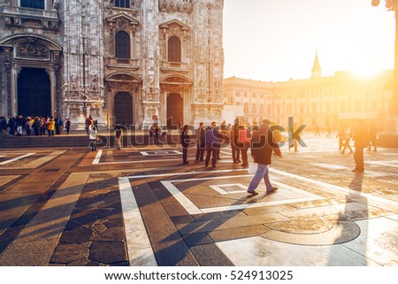 crowd of tourist people walking in center of old town near Duomo in Milan, Italy at sunset time