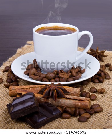 Coffee cup with burlap sack of roasted beans on rustic table