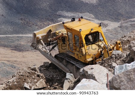 The heavy bulldozer on mountain works at mining operations in mountains
