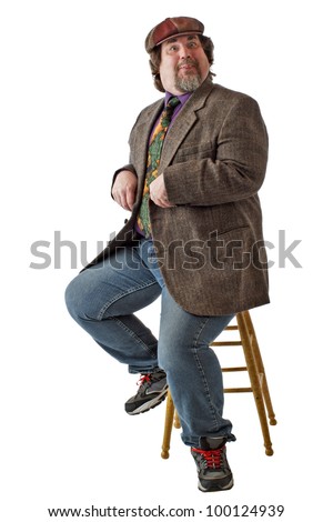 Man with large build sits on stool, dressed casually in tweed cap, jacket and jeans. He is in a funny pose imitating a bird. Vertical, isolated on white background, copy space.